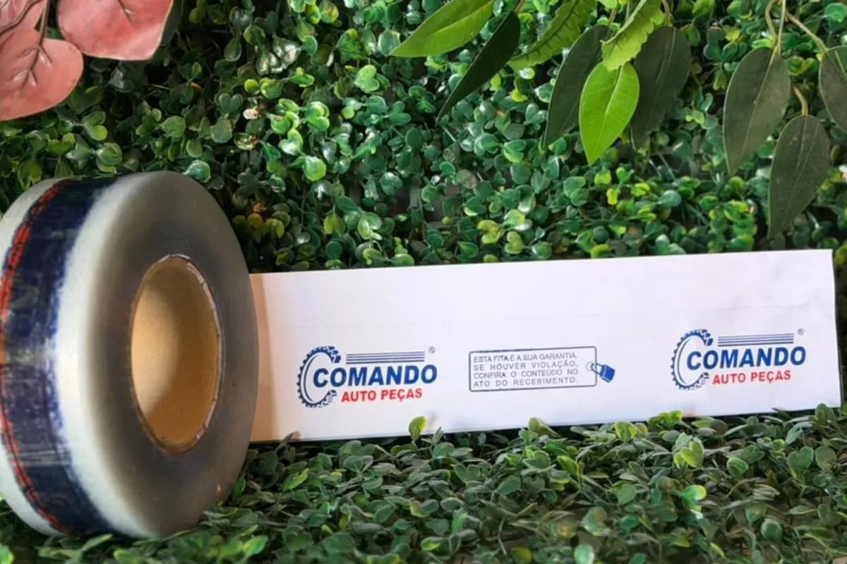 Rolo de fita BOPP transparente impressa e uma tira desenrolada com aviso de garantia contra violação